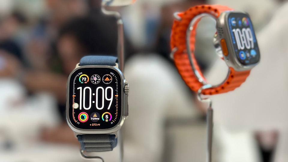Δύο μοντέλα της Apple Watch Ultra 2, στηρίζονταν σε ένα τραπέζι demo. Θολή φόντο.